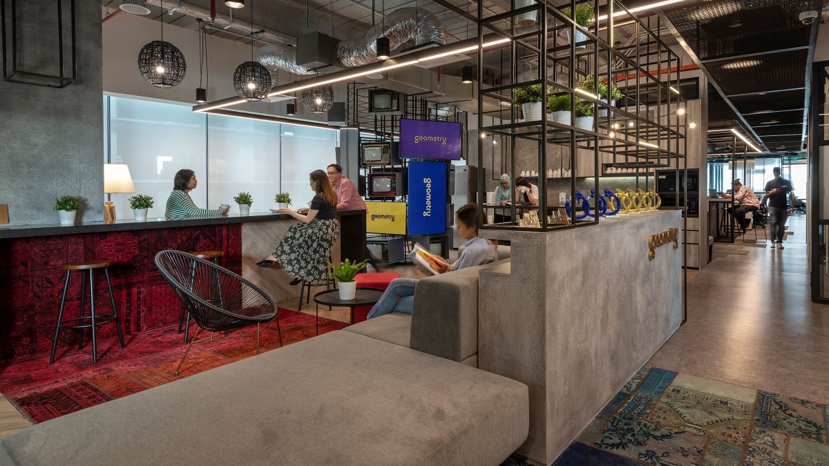 people talking in casual seating area by counter and woman sitting and reading