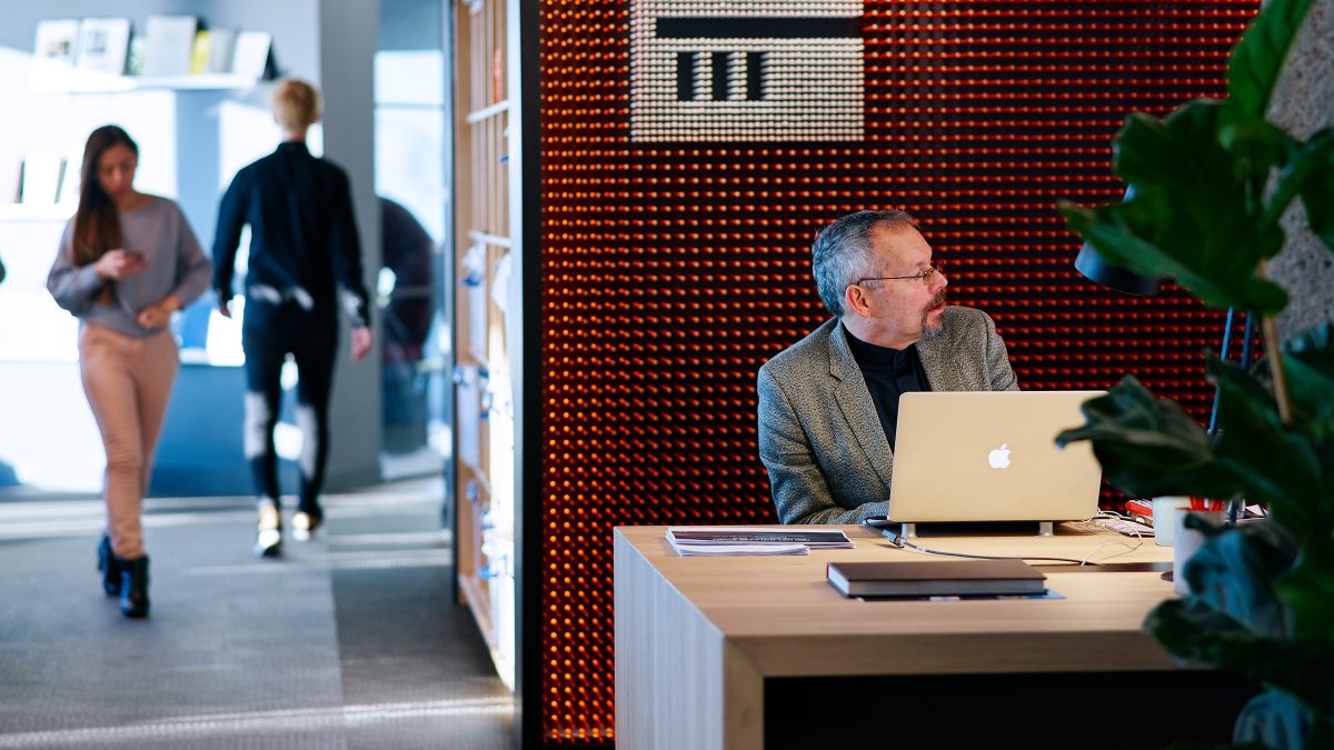 man working at desk and people walking by