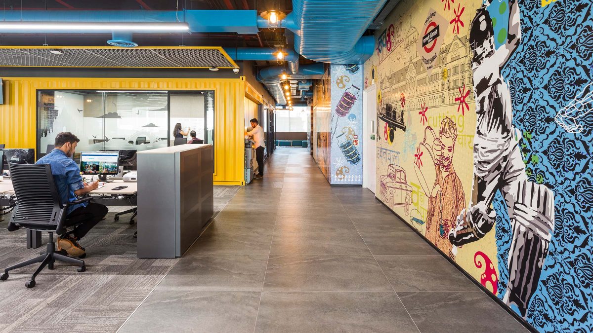 man at desk, people in corridor and view of art mural