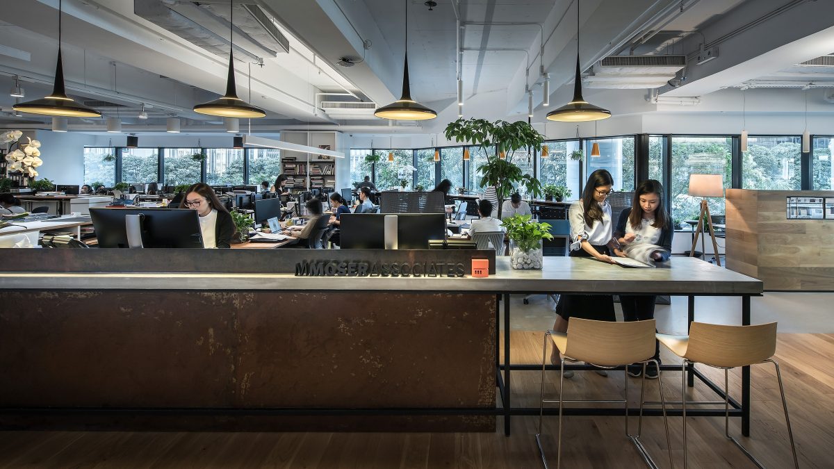 women collaborating while people working behind in open plan area