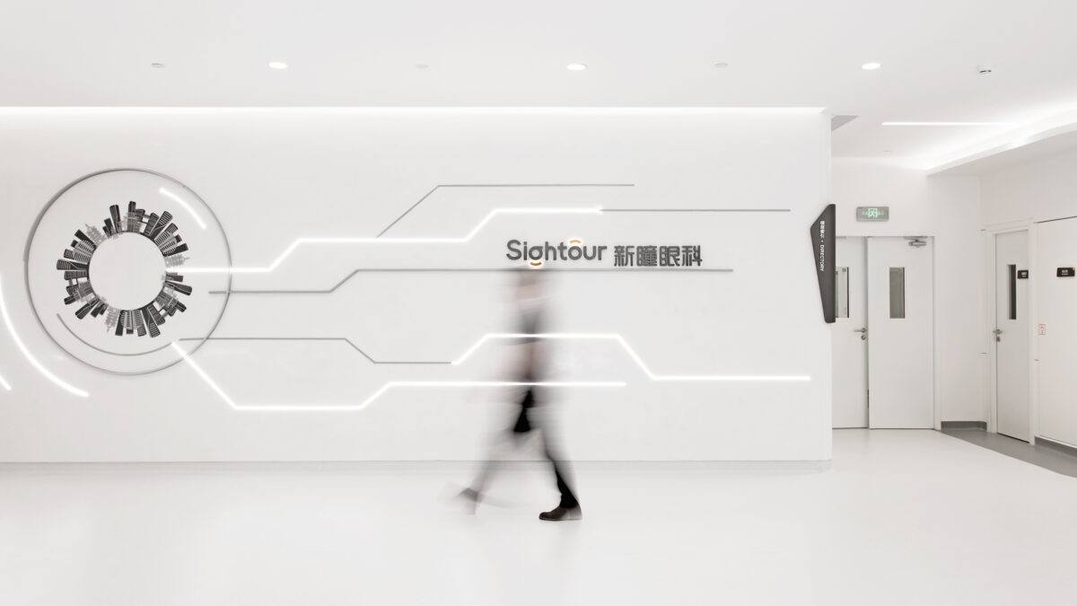 man walking in Sightour Ophthalmic Hospital hallway with logo visible