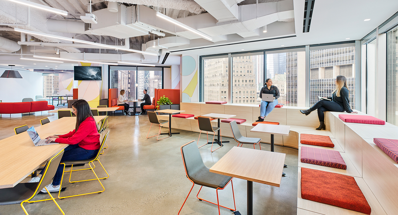 people in casual space, women on tiered seats and woman at desk